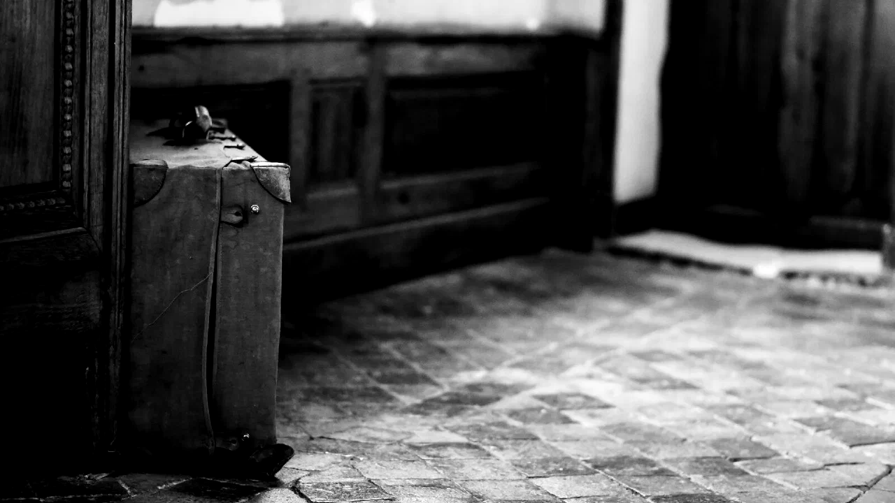 A single suitcase standing on the ground in an empty space