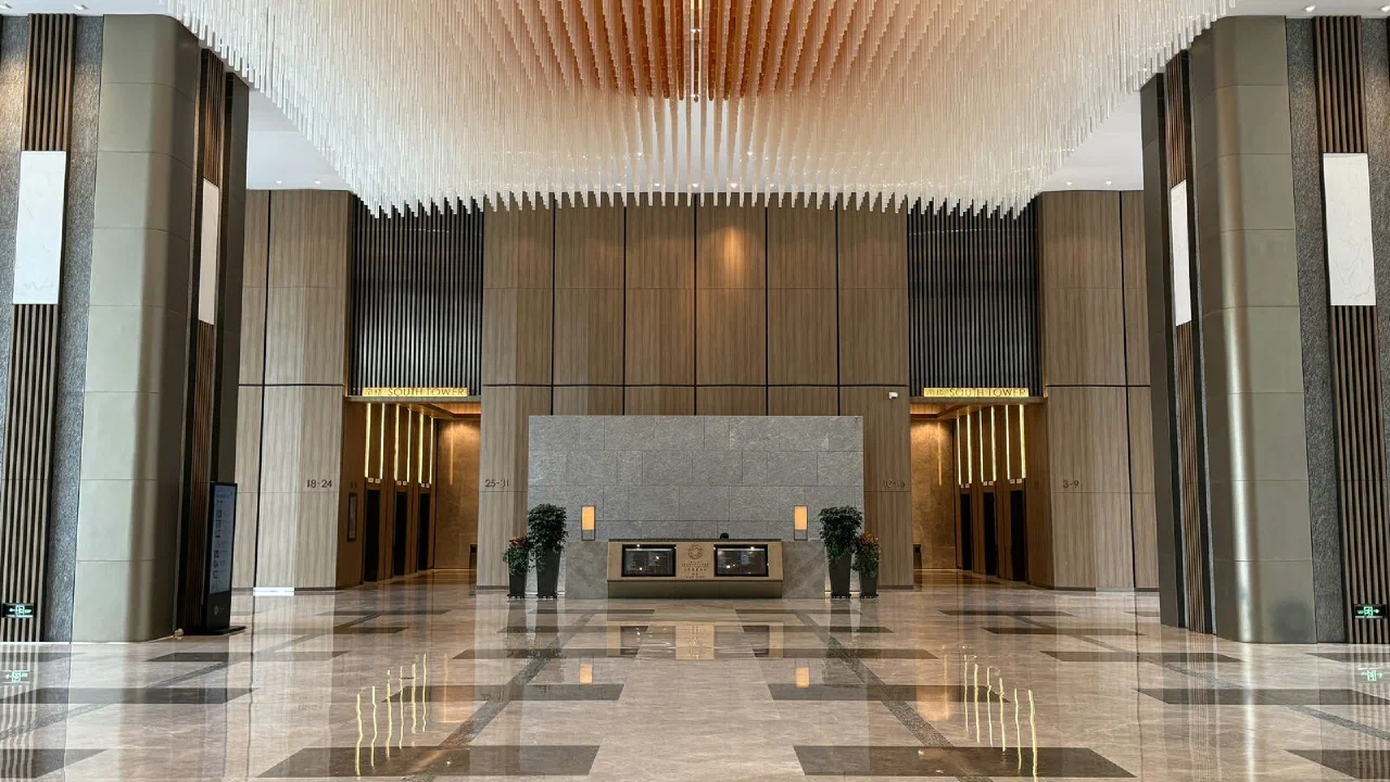 A lobby with marble floors and a high decorative ceiling