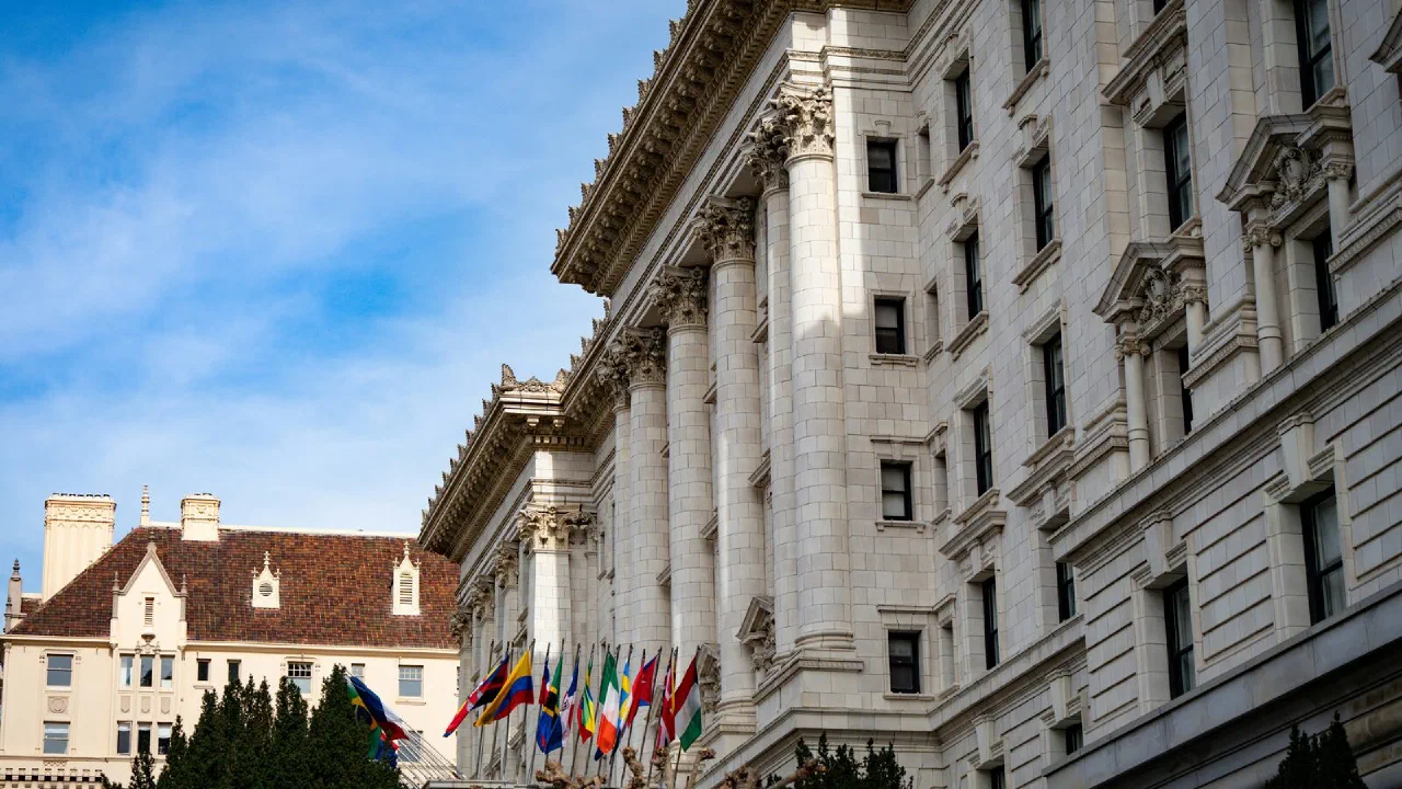 A large official building with stone columns and flagpoles under a clear sky